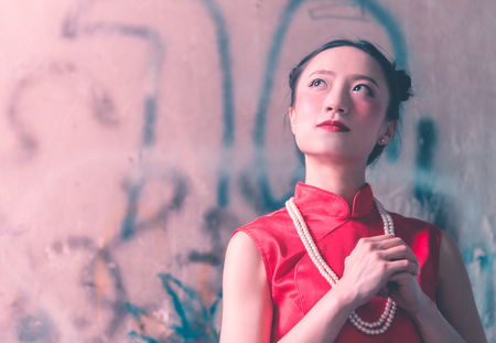 a portrait of Chinese woman wearing Chinese traditional Cheongsam prayingの写真素材