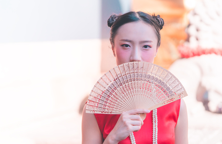 front view of a chinese woman with wooden fan in templeの写真素材
