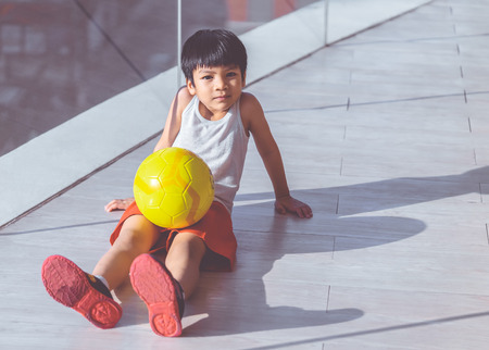 Young boy is sitting with soccer and smilingの写真素材