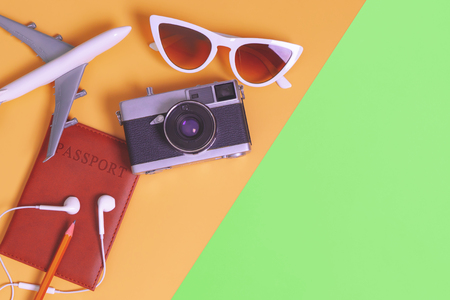 travel objects and accessories on orange green background with passport camera and planeの写真素材