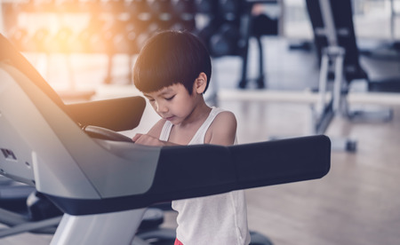 Asian child is running on treadmill in fitness gymの写真素材