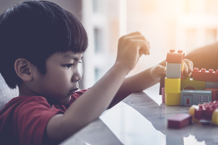 Asian boy stacking Toy blocks on a living room tableの写真素材
