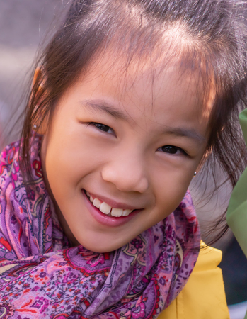 Little smiling girl in winter clothing with scarfの写真素材