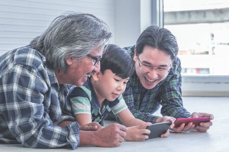 Happy Three generation of male is learning to use Mobile phone internet tohether.の写真素材