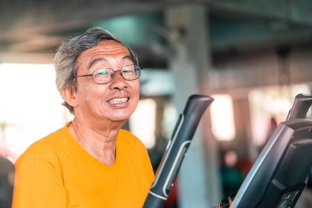 Happy Senior male is working out on fitness machine for elder healthy conceptの写真素材