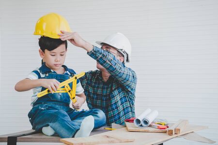 Engineer Father is placing safety hat for his son to teach him about work safetyの写真素材