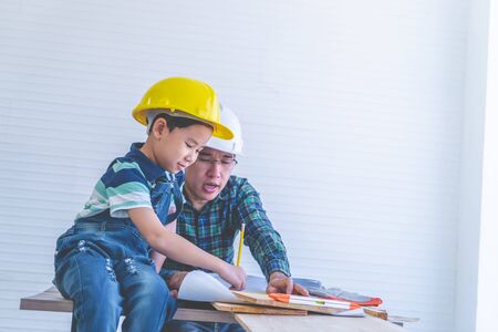 Builder Father is teaching his son to read the construction plan paper.の写真素材
