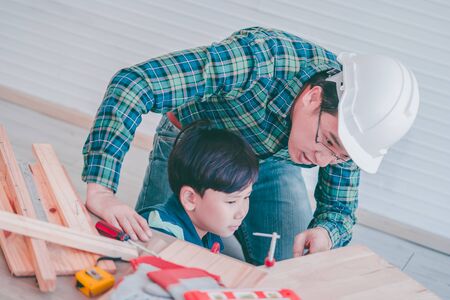 Little Boy is learning to work on wood and be a builder from his craftman fatherの写真素材