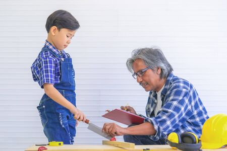 Builder Grandfather is teaching his boy to work on construction woodwork tools.の写真素材
