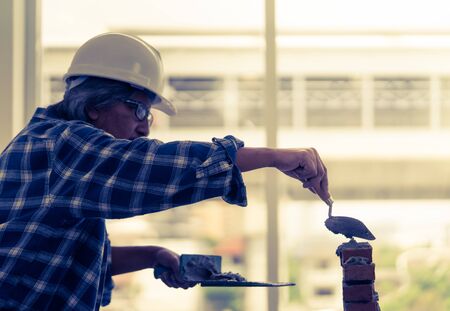 Old Builder craftman is leveling brick wallの写真素材