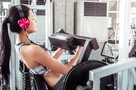 Woman with pink headphone is working out Abs in fitness Machine