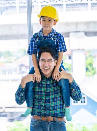 Builder father is carrying his son on his neck for father son success conceptの写真素材
