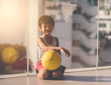 Young boy is sitting with soccer on the floorの写真素材