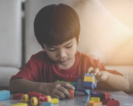 Asian boy stacking Toy blocks on a living room tableの写真素材