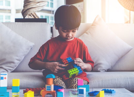 Happy boy stacking Toy blocks on a living room for educational toy