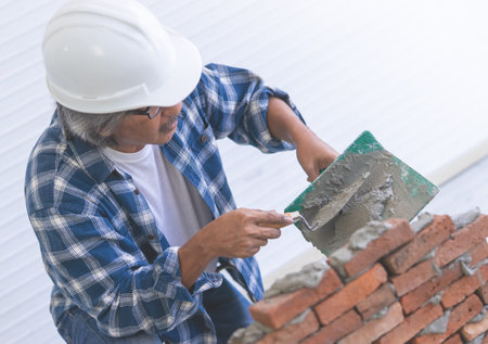 Old Builder craftman is leveling brick wall