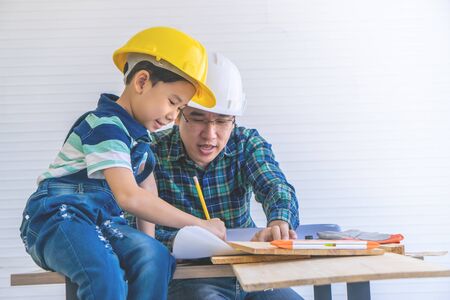Builder Father is teaching his son to read the construction plan paper.の写真素材