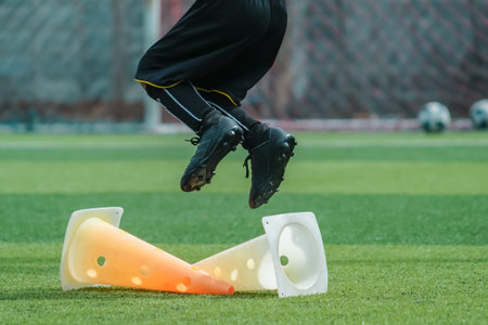 Child feet is practicing Jumping over the cone on soccer field