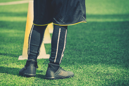 Children feet with soccer boots training on training cone on soccer ground
