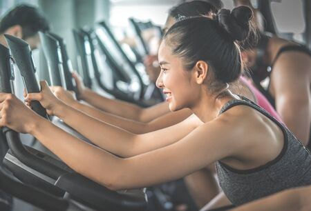 Group of active Woman is line up working out on fitness bike in Fitness Gymの写真素材
