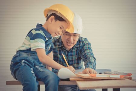 Little Boy is learning to be a builder from his craftman father in vintage toneの写真素材
