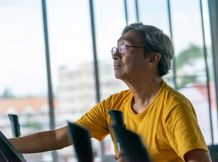 Senior male is working out on fitness machine for elder healthy concept
