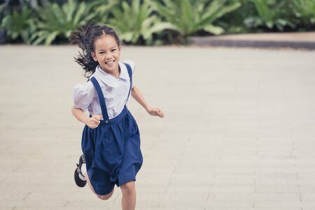 Asian Female Student Kid is running with smile in a garden  with copy space, For Happy education and childhood concept.の写真素材