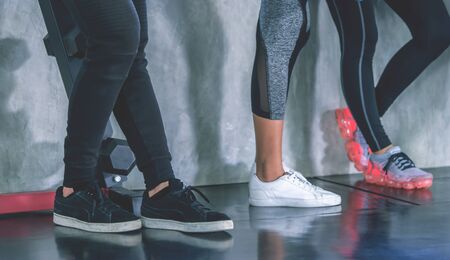 Feet shoes of friends is working out in Fitness Gym with workout equipment, Sport People standing together for sport healthy lifestyle concept.の写真素材