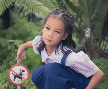 Little girl is pointing at a no dog allowed signate in public parkの写真素材