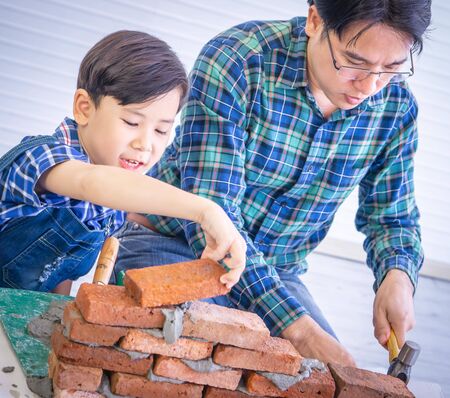 Father builder is teaching his son to lay the brick wall for future career anの写真素材