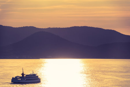 boat ferry is travel along Takamatsu islands in Japan, with golden sunset reflection sky for...