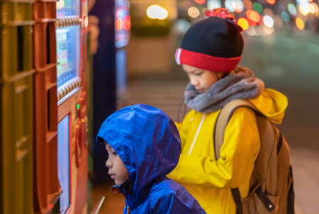 Two children is choosing drinks from Japanese Vending machine near Sendai station at night.のeditorial素材