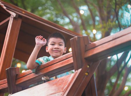 Healthy Asian boy climbing to the top of a wooden playground in public park for healthy and hapyy child conceptの写真素材
