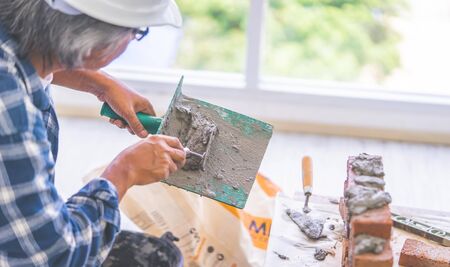 Old Builder craftman is Laying down brick wall in vintage toneの写真素材