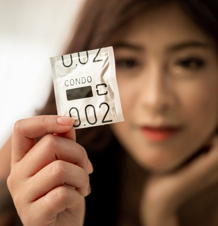 Woman is holding a condom ready to be use in making love for sexual transmittion desease protection...
