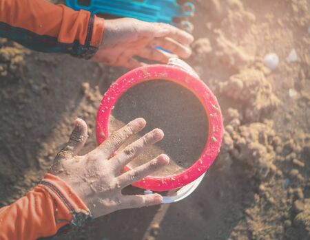 Kid playing with Colorful pink plastic bucket full of sand for kid summer vacation toy concept.の写真素材