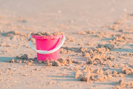 Colorful pink plastic bucket full of sand for kid summer vacation toy concept.の写真素材