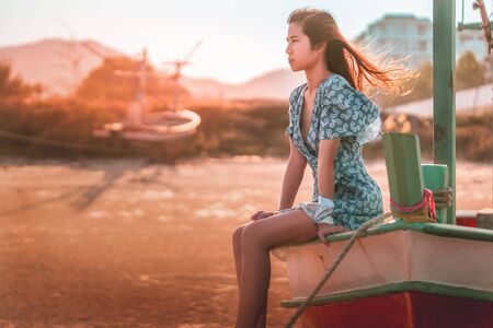 Female tourist is sitting on a Boat on a beach sunset for summer Vacation concept.の写真素材