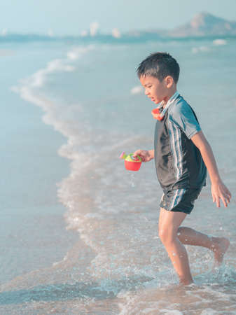 Little boy is playing with wave and sand on Thailand beachの写真素材