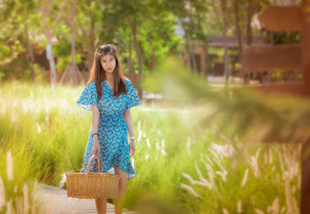 Beauty Farm lady Woman carrying a basket walking in agricultural field for carefree and healthy nature lifestyle concept.の写真素材