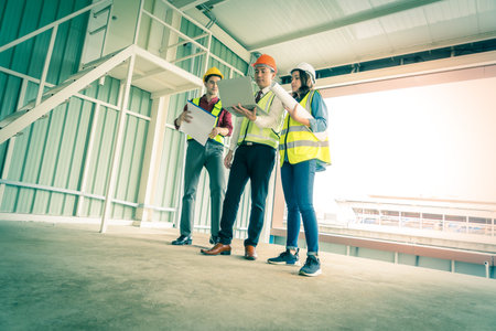 Three engineer male and female is discussing on document and computer in a building construction...