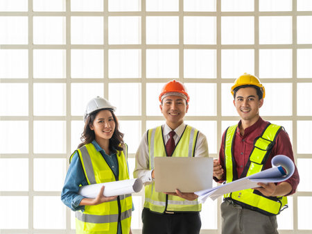 Three engineer male and female portrait with blueprint and computer on bright background.