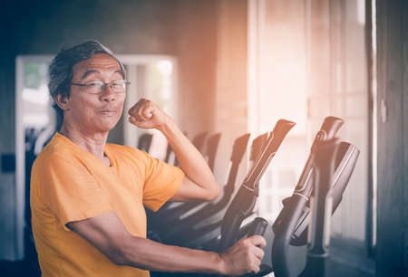 Senior Asian man is working out in fitness gym with confidence muscle show offの写真素材