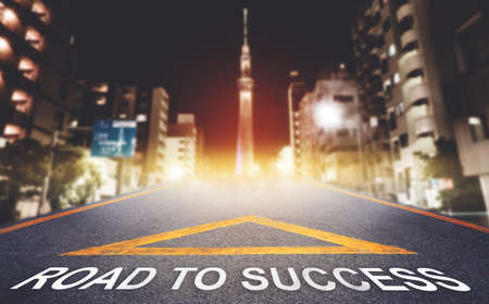 Road to Success arrow sign leading to night Tokyo city skyline for business success and pathway concept.の写真素材