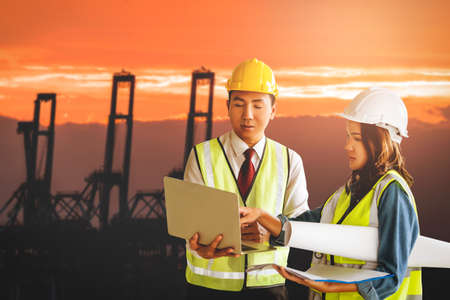 Two Team engineer is standing infront sea port cargo crane harbor terminal for transportation business concept.の写真素材