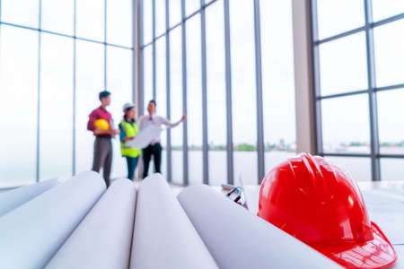 Three contractor team is discussing at the far end of engineer table with building paper drawing.の写真素材