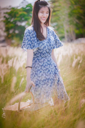 Happy Asian Chinese beautiful looking woman is walking in a field full of nature for freedom nature happy lifestyle concept.の写真素材