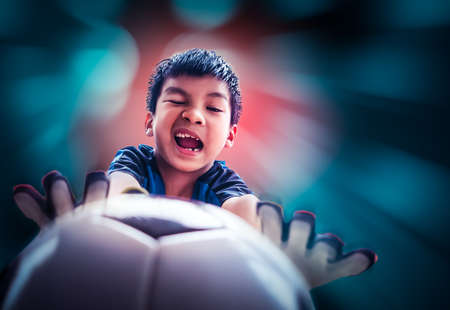 Little football goalkeeper is catching soccer ball with speed motion blue action background.の写真素材