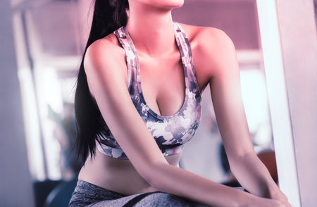 Sporty fitness asian woman is sitting and relaxing in fitness gym wearing sport wear
