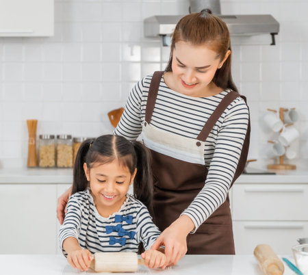 Mother is teaching her child Bakery by rolling flour on the kitchen counter, for family activity...
